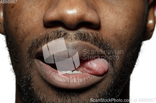 Image of Close up of face of beautiful african-american young man, focus on mouth, stick out tongue