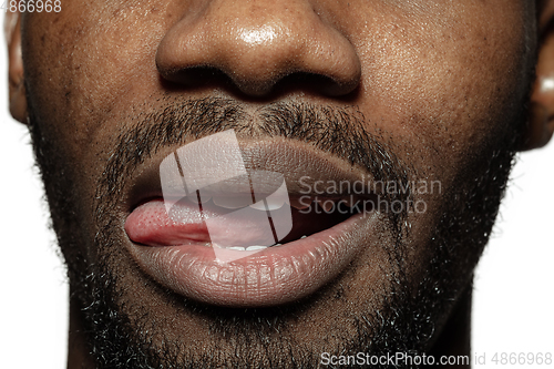 Image of Close up of face of beautiful african-american young man, focus on mouth, stick out tongue