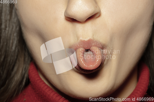 Image of Close-up female mouth with natural nude gloss lips make-up. Cosmetology, dentistry and beauty care, emotions, stick out tongue, fun