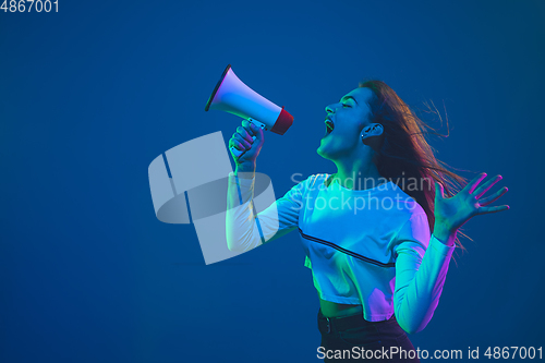Image of Caucasian woman\'s portrait isolated on blue studio background in pink-green neon light, stylish and beautiful