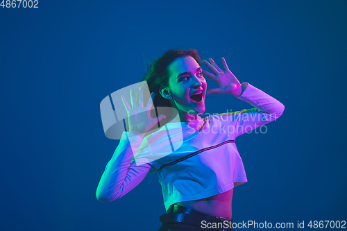 Image of Caucasian woman\'s portrait isolated on blue studio background in pink-green neon light, stylish and beautiful