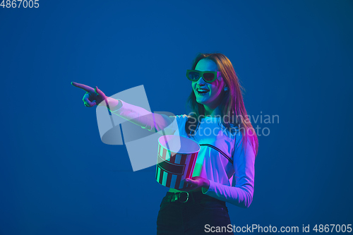 Image of Caucasian woman\'s portrait isolated on blue studio background in pink-green neon light, stylish and beautiful, cinema concept