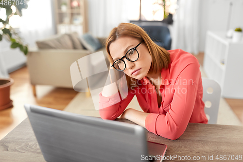 Image of bored woman with laptop working at home office