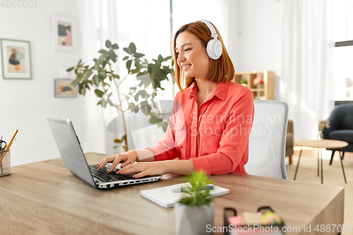 Image of woman in headphones with laptop working at home