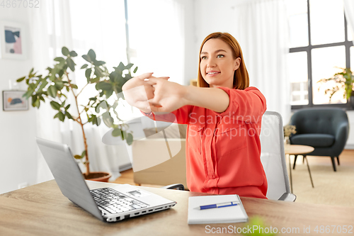 Image of happy woman stretching arms at home office