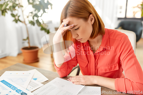 Image of stressed woman with papers working at home office