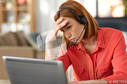 Image of sad woman with headset and laptop working at home