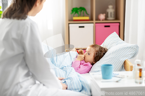Image of doctor and sick little girl in bed at home