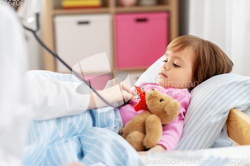 Image of doctor with stethoscope and sick girl in bed