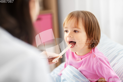 Image of doctor checking sick girl's throat at home