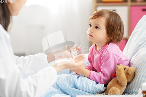 Image of doctor giving medicine to sick girl in bed at home