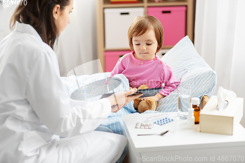 Image of doctor with tablet computer and sick girl in bed