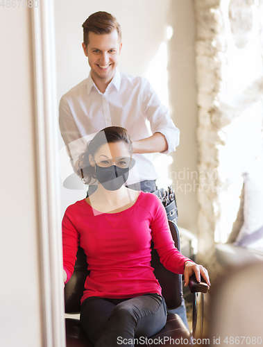 Image of happy woman with stylist making hairdo at salon