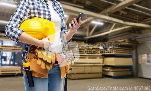 Image of female worker with phone and tools at factory