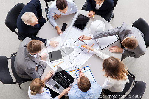 Image of architects with laptop and blueprint at office