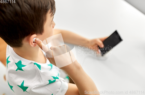 Image of boy with earphones and smartphone at home