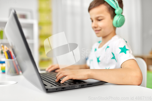 Image of boy in headphones playing video game on laptop