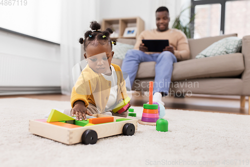 Image of african baby girl playing with toy blocks at home