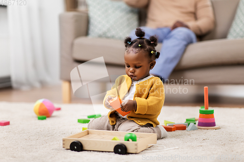 Image of african baby girl playing with toy blocks at home