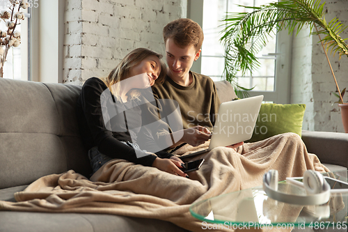 Image of Attractive young couple using devices together, tablet, laptop, smartphone, headphones wireless. Gadgets and technologies connecting people all around the world