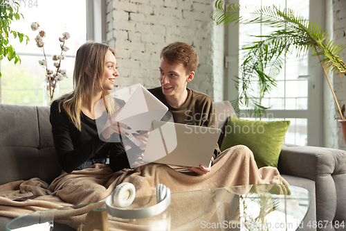 Image of Attractive young couple using devices together, tablet, laptop, smartphone, headphones wireless. Gadgets and technologies connecting people all around the world