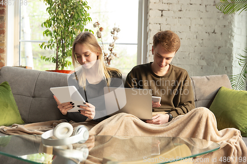 Image of Attractive young couple using devices together, tablet, laptop, smartphone, headphones wireless. Gadgets and technologies connecting people all around the world