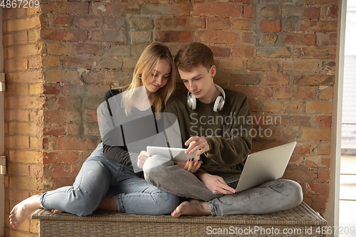 Image of Attractive young couple using devices together, tablet, laptop, smartphone, headphones wireless. Gadgets and technologies connecting people all around the world