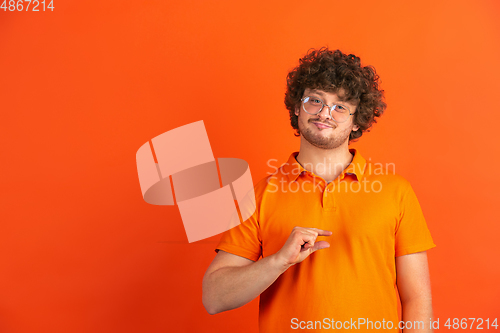 Image of Caucasian young man\'s monochrome portrait on orange studio background