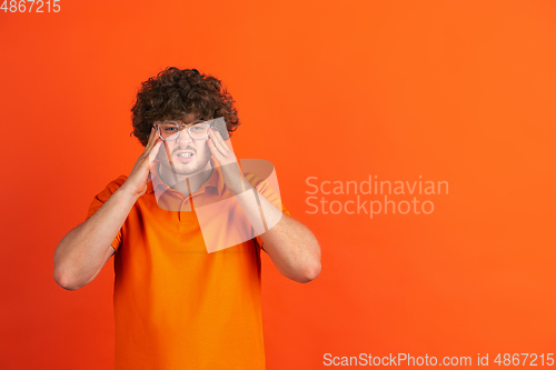 Image of Caucasian young man\'s monochrome portrait on orange studio background