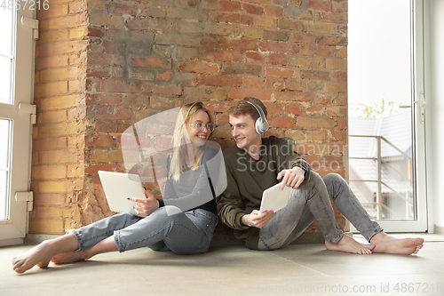 Image of Attractive young couple using devices together, tablet, laptop, smartphone, headphones wireless. Gadgets and technologies connecting people all around the world