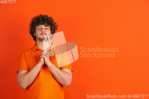 Image of Caucasian young man\'s monochrome portrait on orange studio background