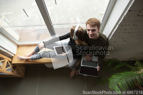 Image of Attractive young couple using devices together, tablet, laptop, smartphone, headphones wireless. Gadgets and technologies connecting people all around the world. Top view