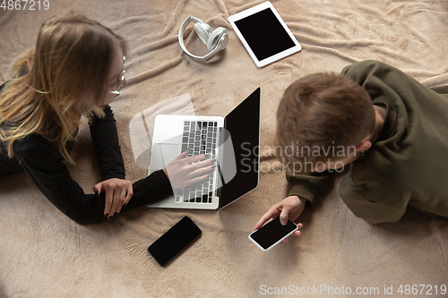 Image of Attractive young couple using devices together, tablet, laptop, smartphone, headphones wireless. Gadgets and technologies connecting people all around the world