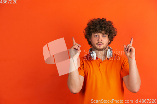 Image of Caucasian young man\'s monochrome portrait on orange studio background