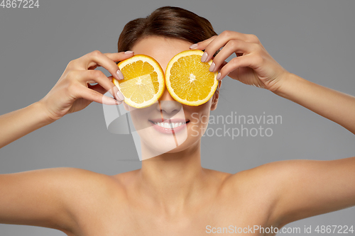 Image of beautiful woman making eye mask of orange slices