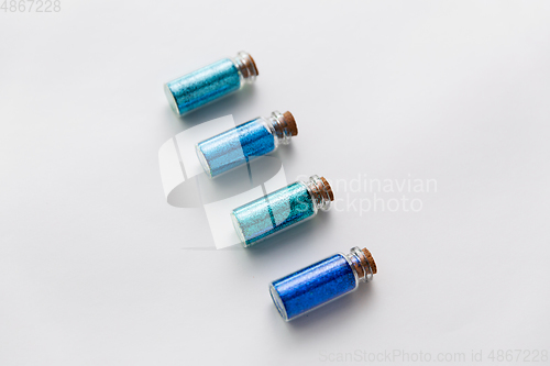 Image of blue glitters in bottles over white background