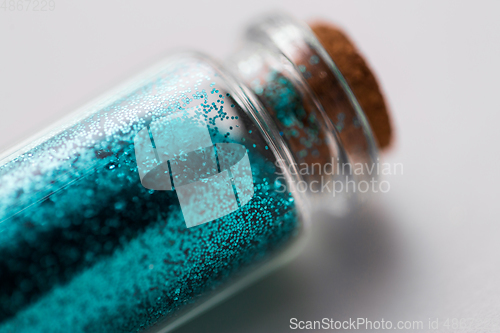 Image of blue glitters in bottle over white background