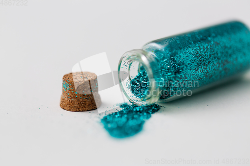 Image of blue glitters poured from small glass bottle