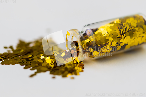 Image of golden glitters poured from small glass bottle