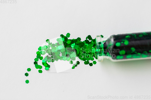 Image of green glitters poured from small glass bottle