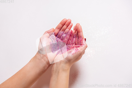 Image of hands holding glitters on white background