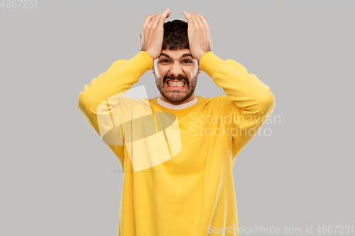 Image of angry young man holding to head