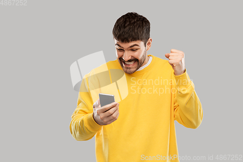 Image of happy smiling young man with smartphone