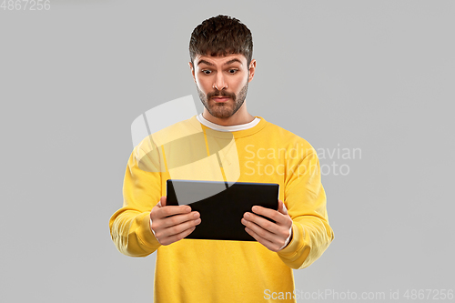 Image of surprised young man with tablet pc computer