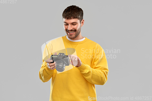 Image of smiling young man with digital camera