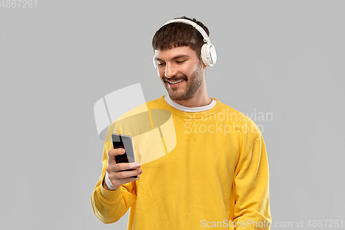 Image of smiling young man with headphones and smartphone