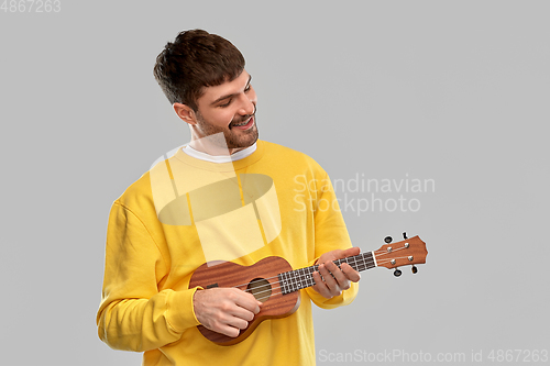 Image of smiling young man playing ukulele guitar