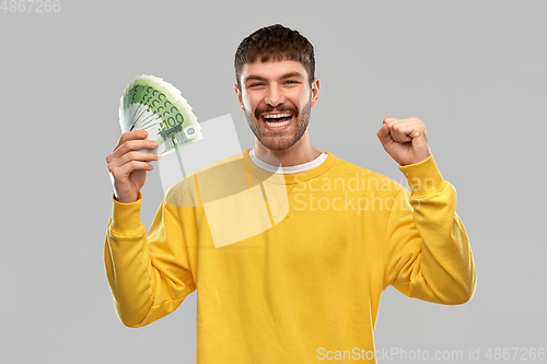 Image of happy young man with money celebrating success