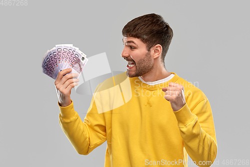 Image of happy young man with money celebrating success