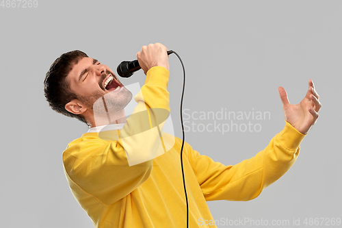 Image of man in yellow sweatshirt with microphone singing